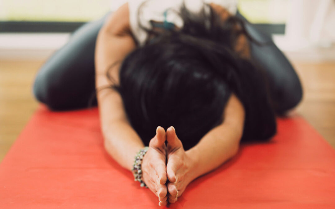 Una donna che fa esercizi di Yoga distesa per terra