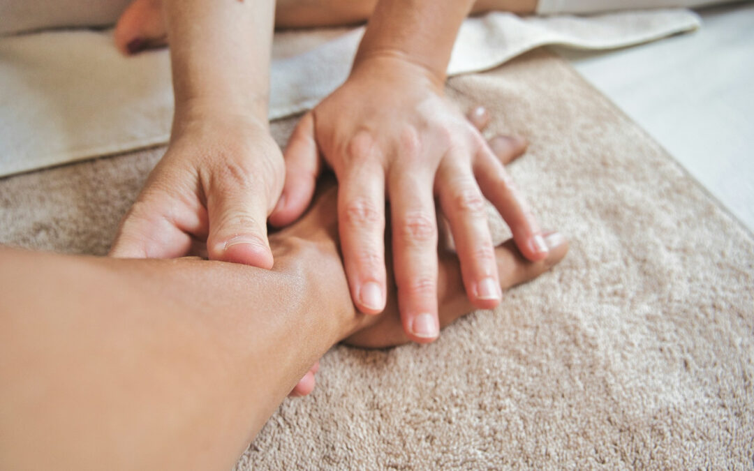 La mano di una persona massaggia il polso e l'avambraccio di un'altra persona.