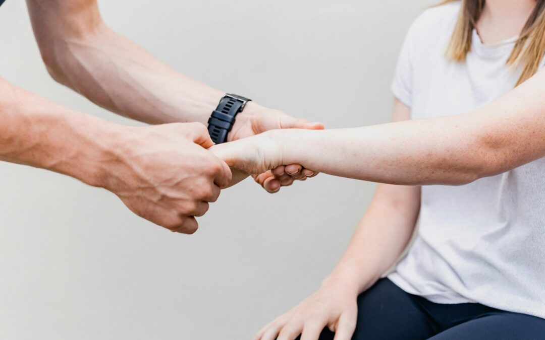 Un paio di mani di un fisioterapista testano la mano di una paziente.